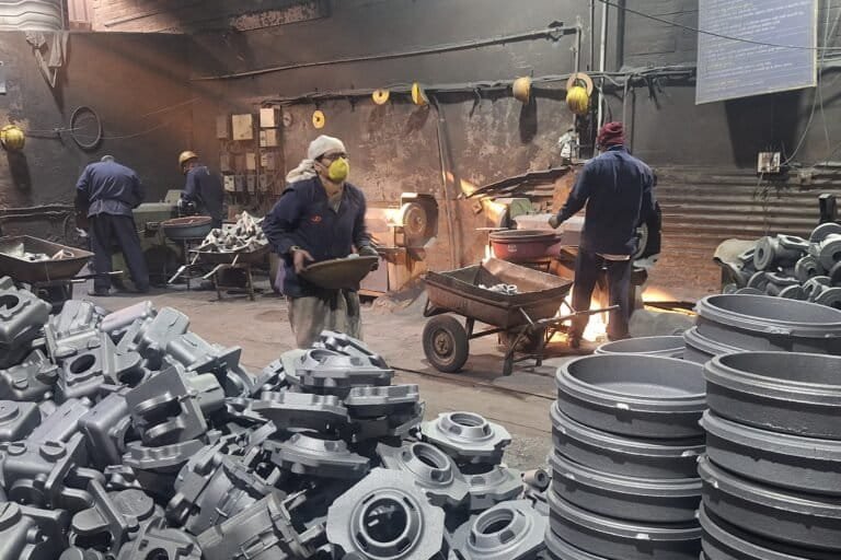 Workers arrange metal castings.