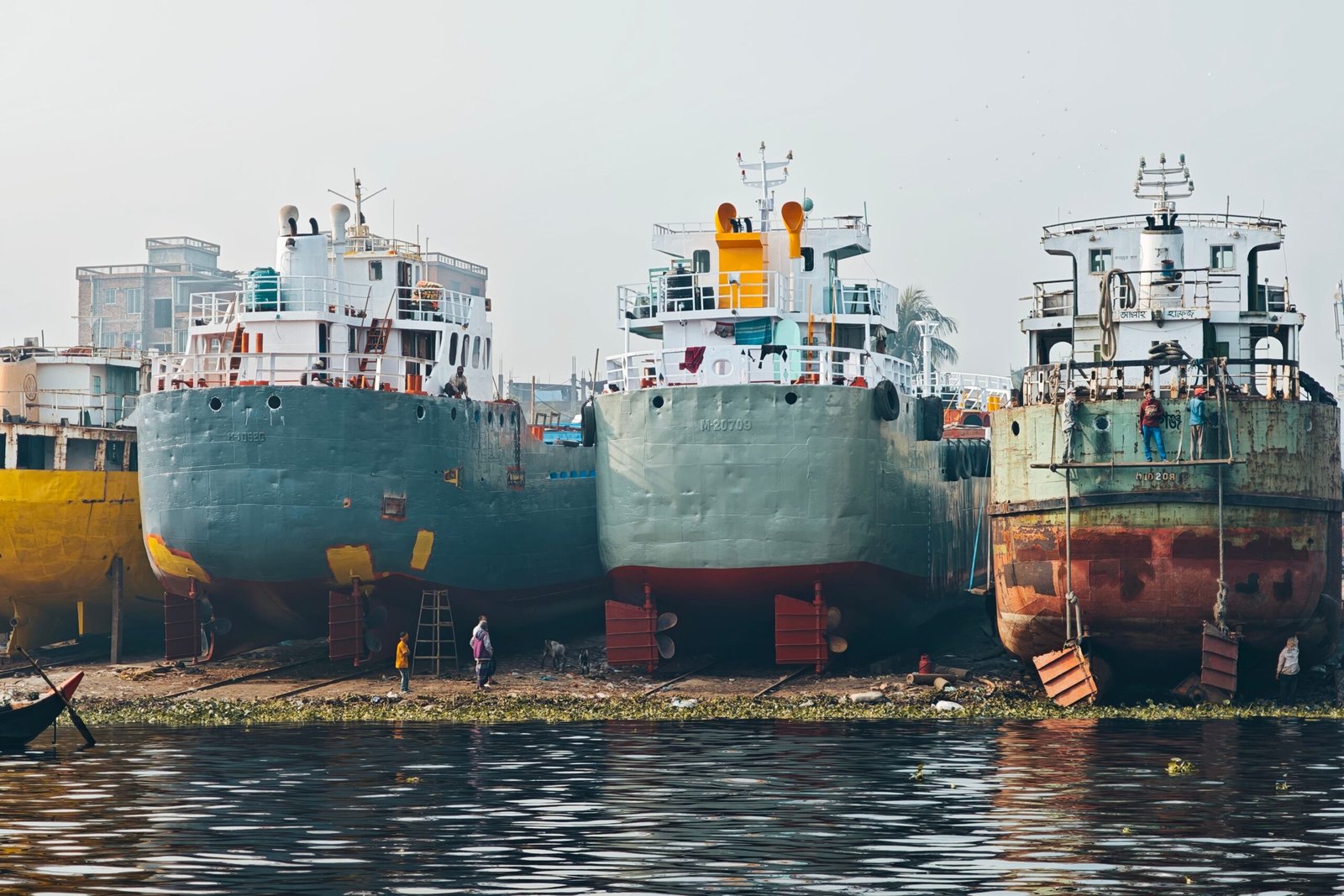 Row of large cargo ships docked at an industrial shipyard.